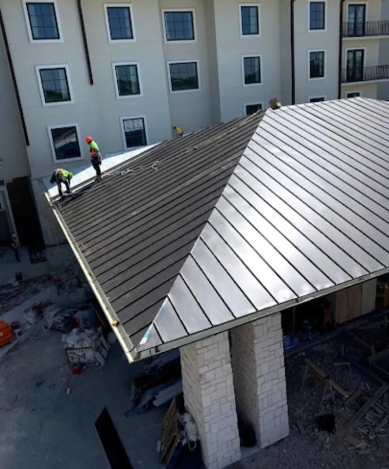 Crew installing standing seam metal roof panels on a commercial project in Prosser